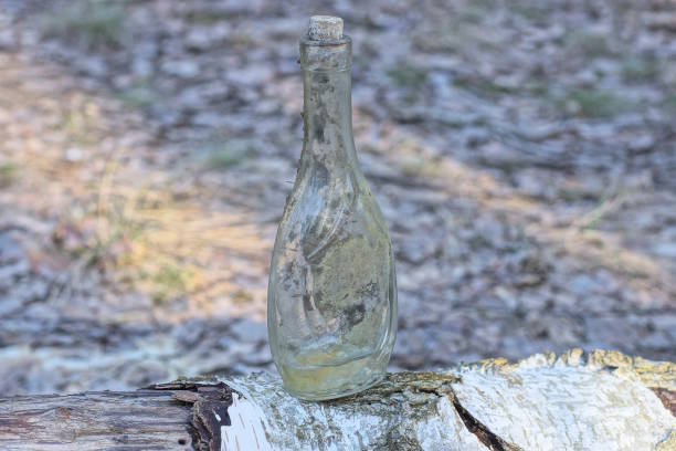 one old dirty gray glass bottle stands on a white table outside