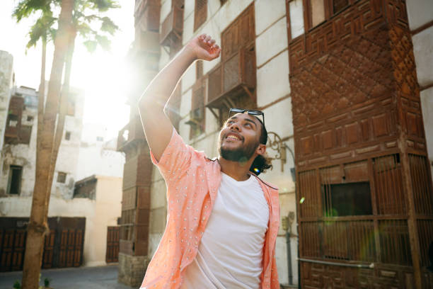 istock Happy young Saudi man cheering with arm raised 2156001690
