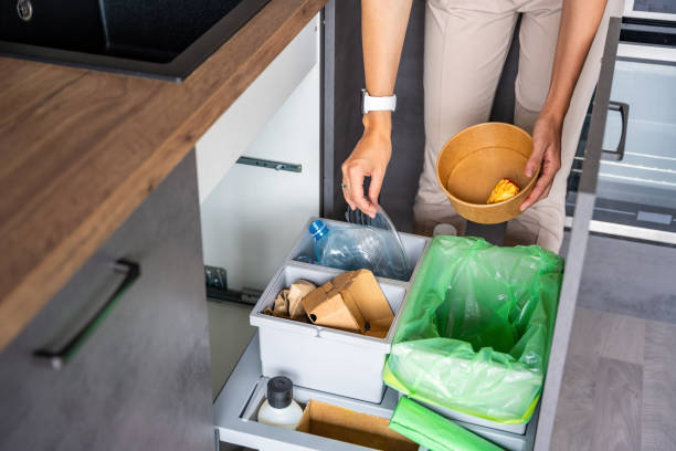 istock Woman throwing trash into household bins for waste sorting in the kitchen for recycle. Plastic, paper, bio and mixed waste. Sorting waste at home concept 2156001822