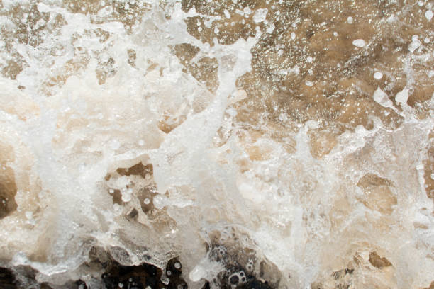 istock Beach water hitting the dark rocks. 2156001870