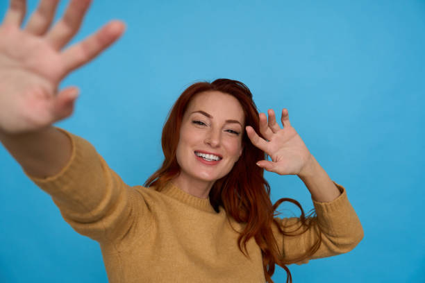 istock Happy redhead waving and smiling on blue 2156001963