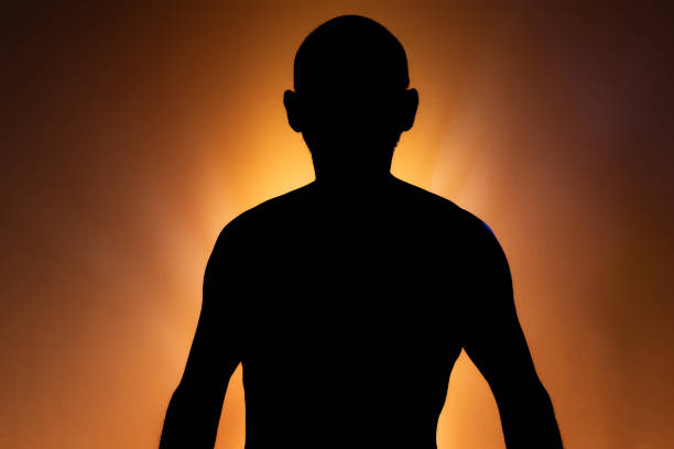 istock Man in silhouette, standing still and shirtless, posing for a photo. 2156003321