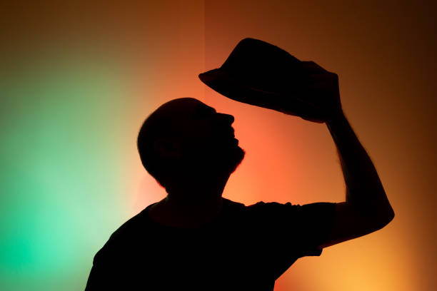 Studio portrait of a man holding hat in silhouette. Isolated on colored background.