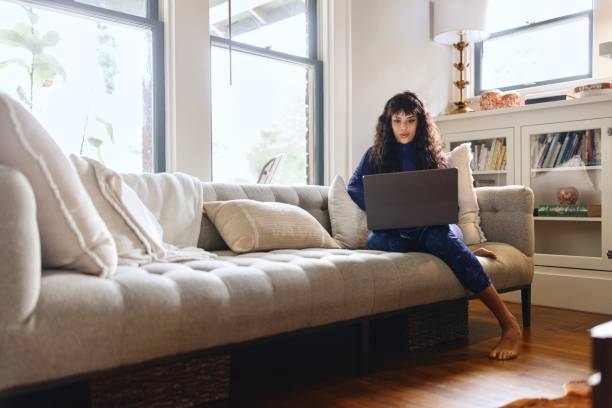 istock Modern woman sitting on the sofa while working from home 2156005853