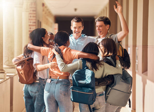 istock Group of people, happy students and hug for education celebration, interracial support or study project success. Diversity, university friends celebrate  and hugging happiness in building corridor 2156006443