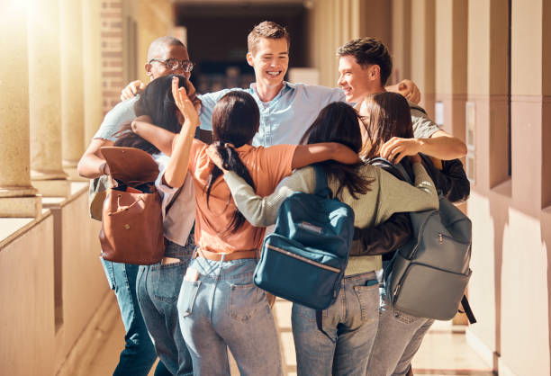 University, students and diversity friends hug at campus in support, motivation and happiness together in education, studying and learning. Happy, excited and young college people group in solidarity