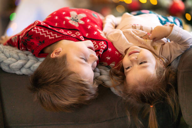 Two happy brother and sister lying on sofa at Christmas