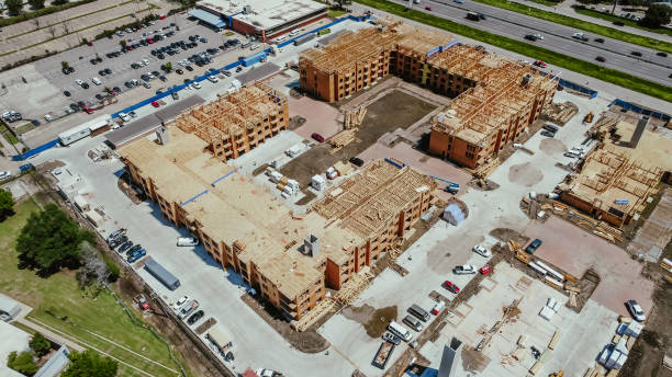 istock Aerial view workers and heavy industrial machines working at apartment complex construction, timber wood frame, elevator vertical shaft, large courtyard, slab foundation in downtown Dallas, Texas 2156010433