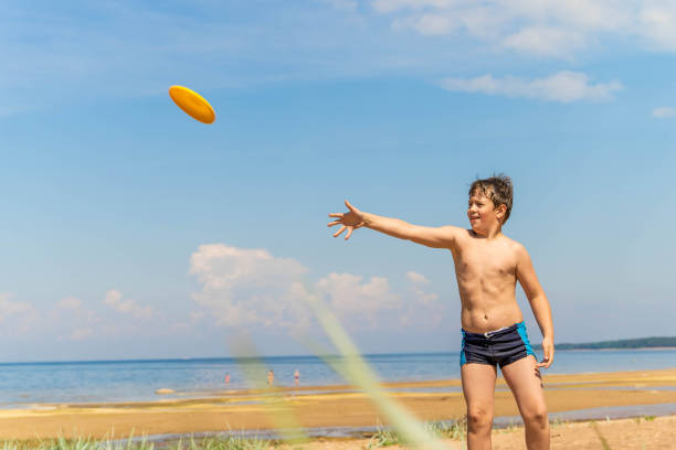 istock A young boy throws a frisbee on a sandy beach during a summer vacation. play, flying saucer 2156011320