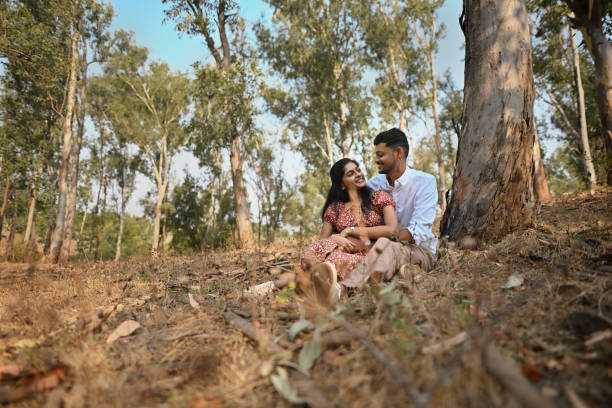 istock Young romantic Couple in each  others arms sitting under a Tree 2156012649