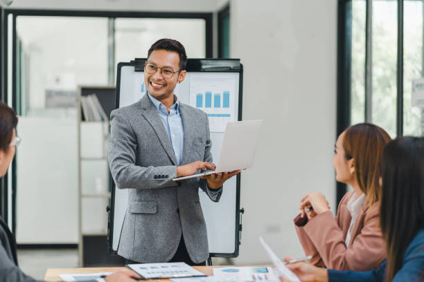 istock Businessman in a grey suit leads a presentation with charts and graphs in a modern office. 2156013433
