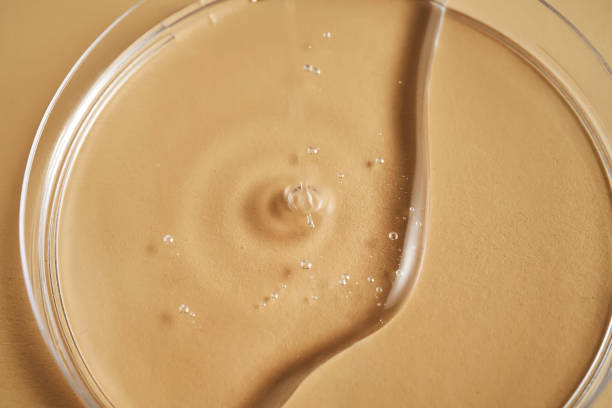 istock Serum or cosmetic oil flows into a transparent bowl. 2156015611