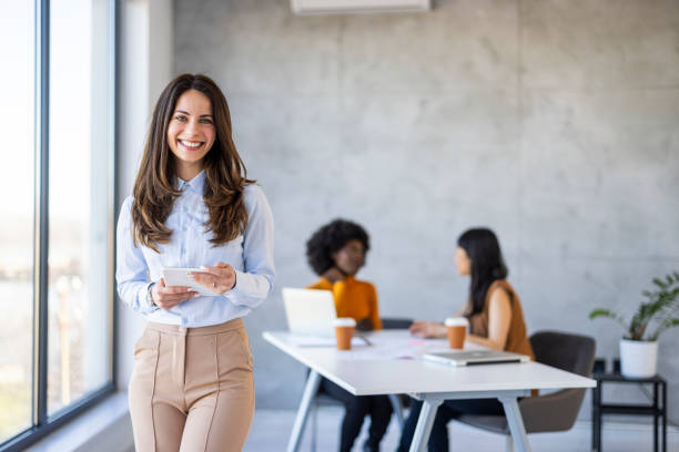 istock Smiling Woman with Tablet in Contemporary Office Space 2156017648