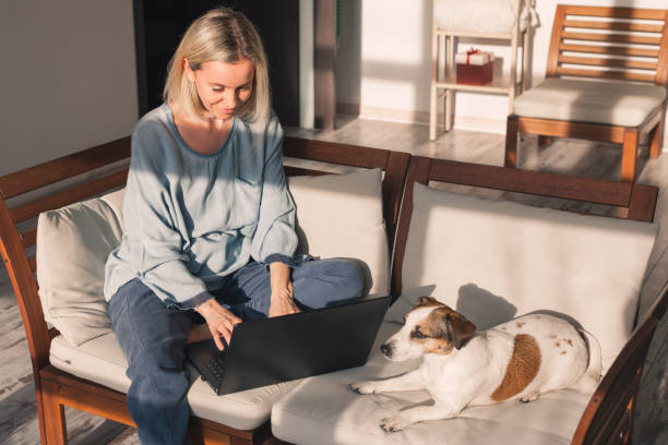 istock Happy middle aged woman using her laptop on the sofa at home 2156019746