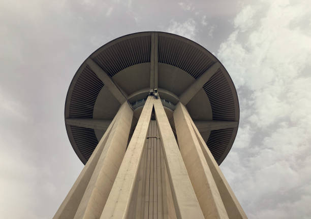 A tall water tower stands prominently against a bright blue sky, highlighting its metallic structure and ladder. It reflects industrial design in a city setting