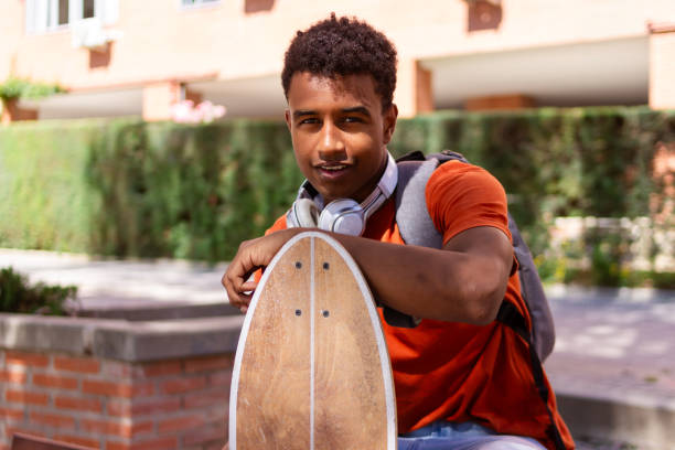 Young man is sitting on a bench with his skateboard after class