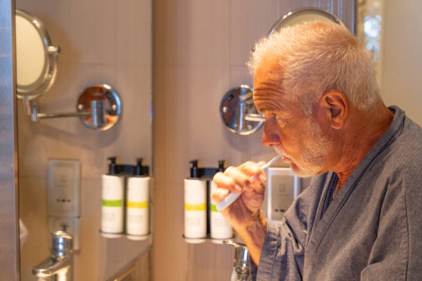 istock Senior Man Brushing Teeth Up Close in Hotel Bathroom 2156033268
