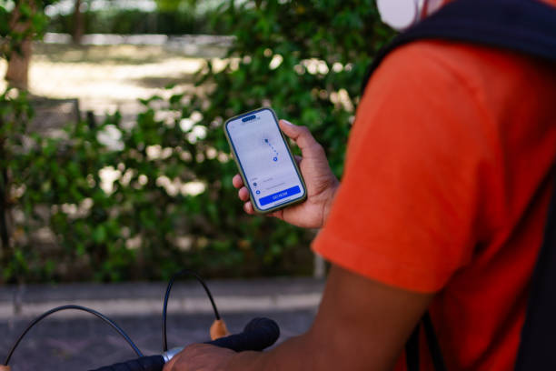 istock Delivery man using gps on phone while riding bike 2156033327