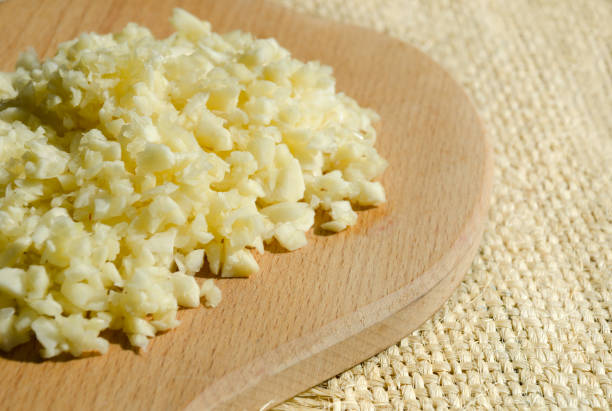 istock Sliced garlic on a wooden cutting board on a burlap background. 2156034056