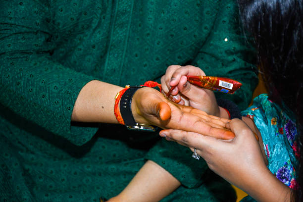 istock People standing with hands touching, holding out an object together in a Mehndi Ceremony 2156035029