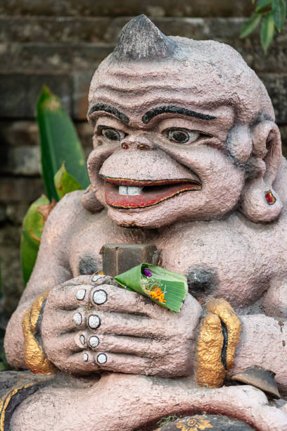 istock a statue sitting in front of a building holding a small plant 2156038135