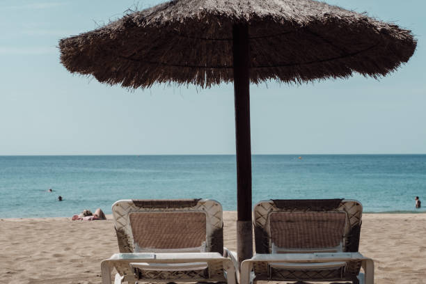 Beautiful photo of feet lying on a sandy beach with a blue and white towel.