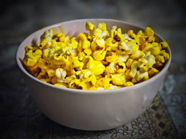 A bowl of popcorn on a wooden table surface