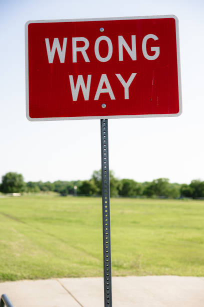 istock Wrong way sign on a street post in a grassy field 2156047146