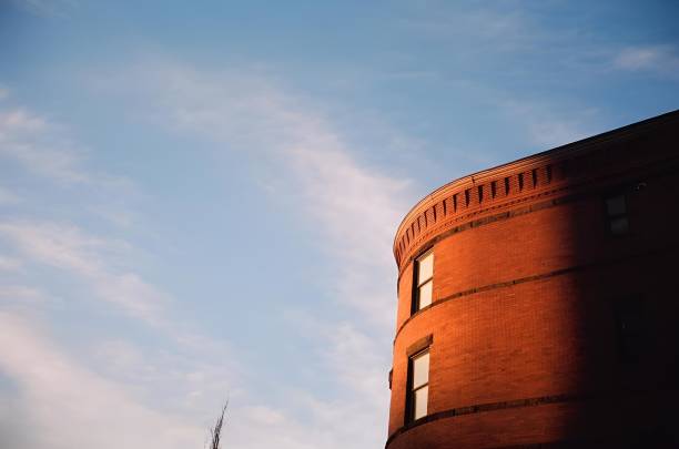 A circular building with closed windows against a sky backdrop in Boston captured on film