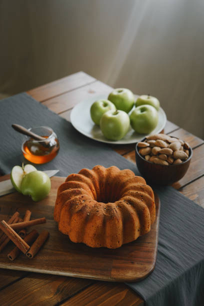 A top view of a pudding on a cutting board with apples, cinnamon, and honey