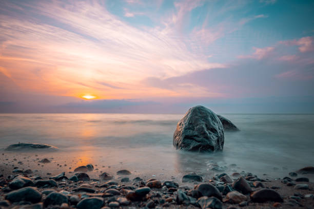 A rock on a beach shore during the sunset