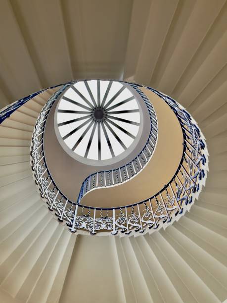 A top-down view of a modern spiral staircase with curved marble steps and glass railings.