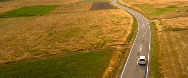 istock Car on the winding road between the golden fields 2156058471