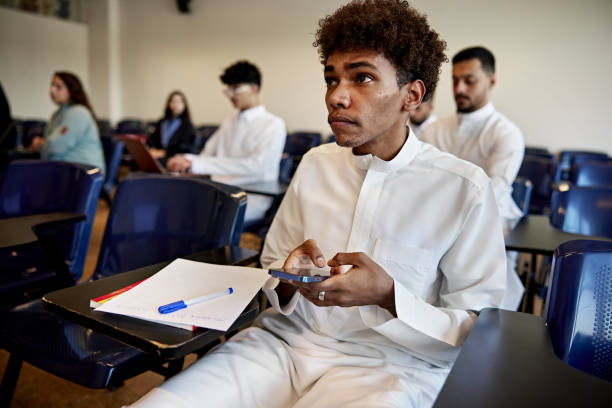 istock Male student holding phone sitting in class 2156059055