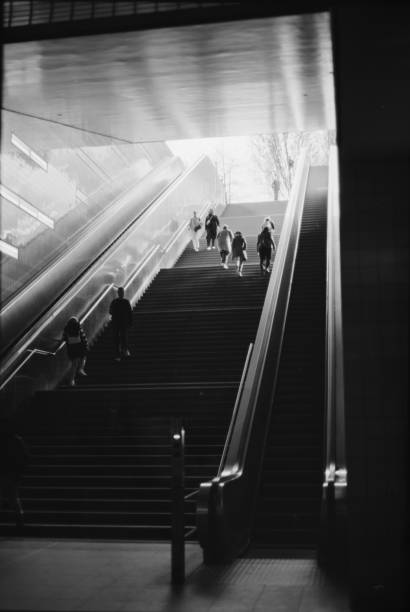 A monochrome image of people descending on escalator