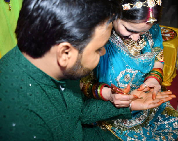 istock People standing with hands touching, holding out an object together in a Mehndi Ceremony 2156061170