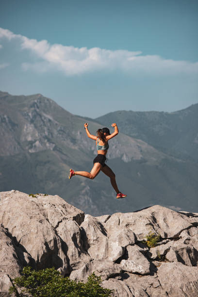 Woman athlete leaping over rocks atop a mountain