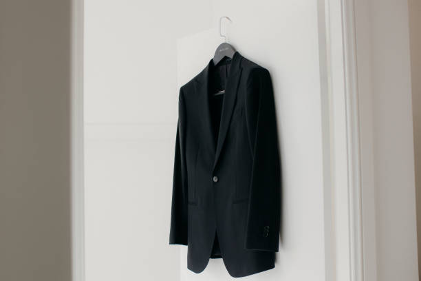 istock Man's suit hanging on a hook against a white wall 2156062020