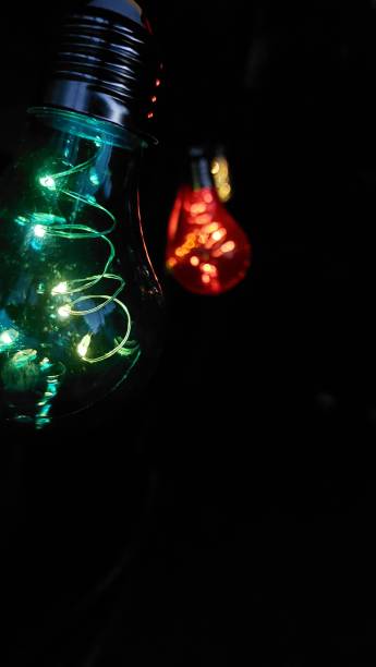 istock a light bulb glowing on a dark background with colored christmas lights in the bulb 2156063131