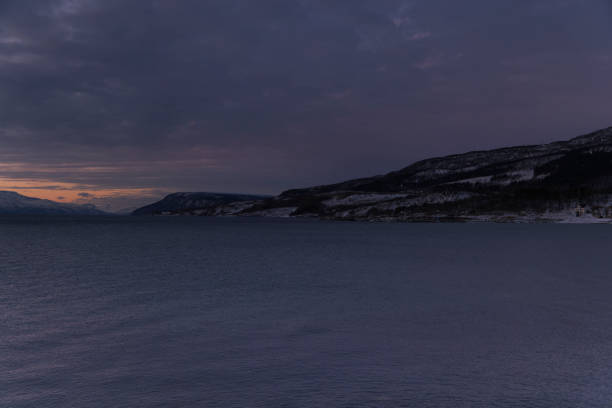 The Sun setting over snow-covered field with mountains in the background