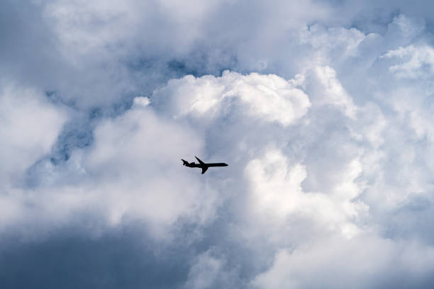 A small airplane flying amidst large clouds in a blue sky