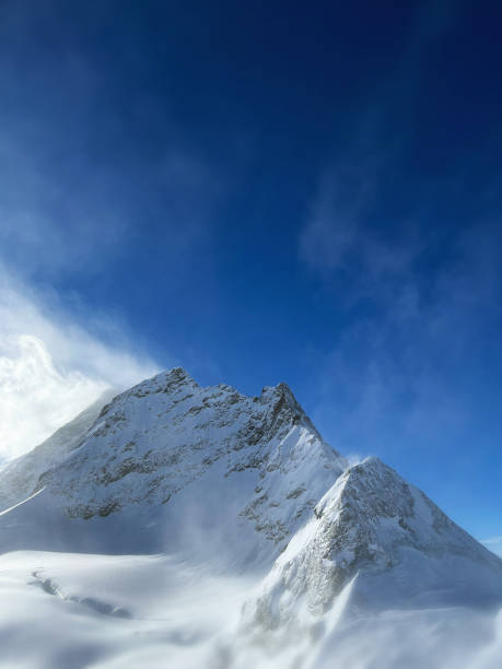 istock Tall mountain covered in snow with its peak in the clouds 2156065004
