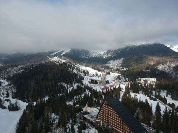 istock Snowy mountain range with ski lodge on top and snow-covered hill 2156065075