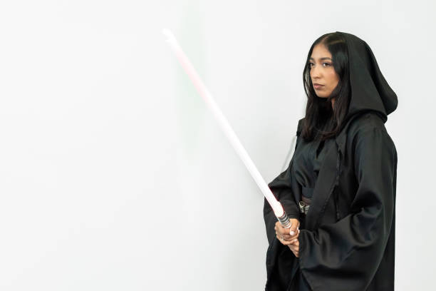 istock Woman in robes wields a light sword against a white wall backdrop 2156068335
