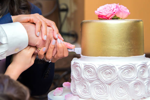 istock Newlyweds use a knife to cut the wedding cake 2156068827