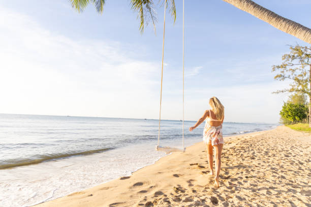 istock Woman Walking Along a Tropical Beach at Sunset 2156072490