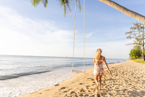 istock Woman Walking Along a Tropical Beach at Sunset 2156072493