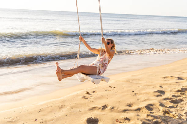 istock Woman Relaxing on a Swing by the Ocean 2156072612