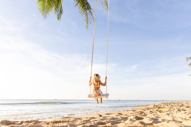 istock Woman Swinging Above a Tropical Beach at Sunset 2156072625
