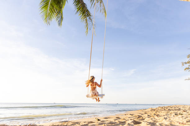 istock Woman Swinging Above a Tropical Beach at Sunset 2156072661
